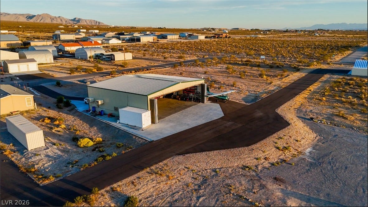 A spacious airplane hangar sits alongside paved taxiways in a scenic desert landscape.