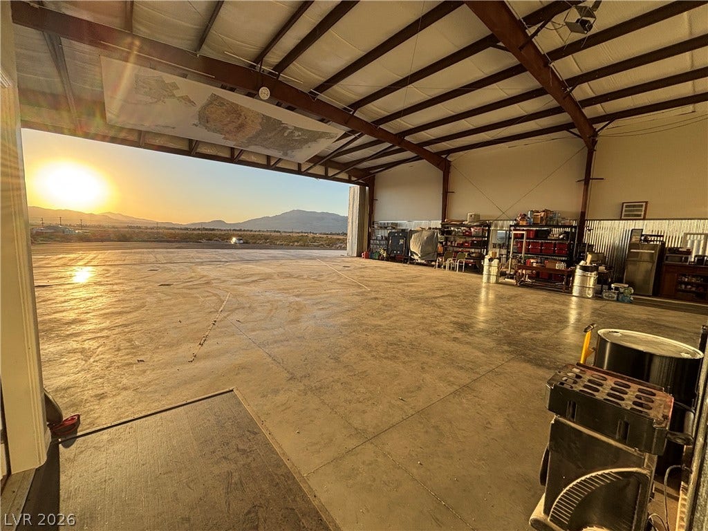 A spacious aircraft hangar features concrete flooring under an expansive exposed steel beam ceiling.