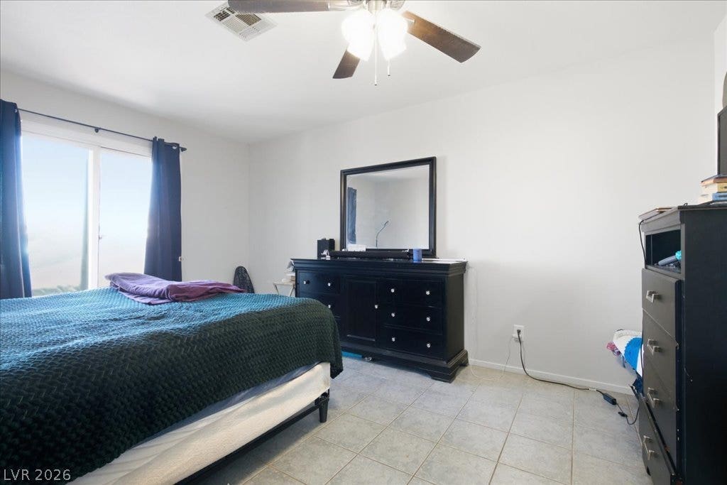 3960 Grapefruit Circle, Las Vegas, NV 89103 Tiled flooring and a sliding glass door define this bright bedroom space.