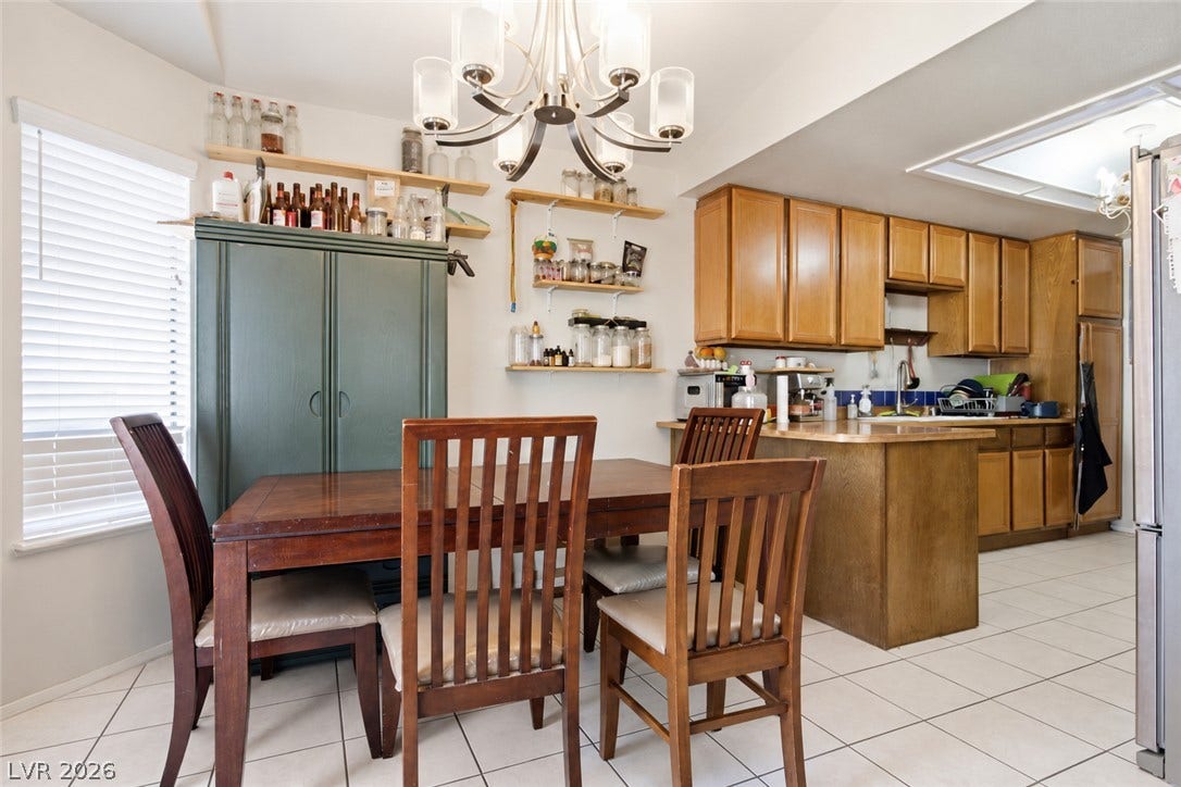 3960 Grapefruit Circle, Las Vegas, NV 89103 Tiled flooring and a classic chandelier define this functional dining and kitchen space.