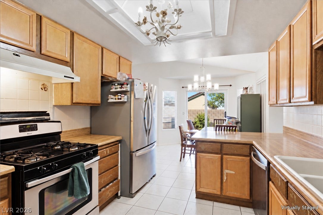 3960 Grapefruit Circle, Las Vegas, NV 89103 Classic wooden cabinetry and tiled flooring define this bright kitchen layout with a casual dining area.