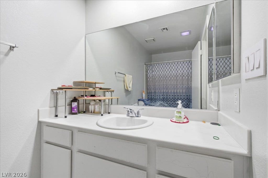 3960 Grapefruit Circle, Las Vegas, NV 89103 A clean white vanity features a large mirror reflecting the shower area.