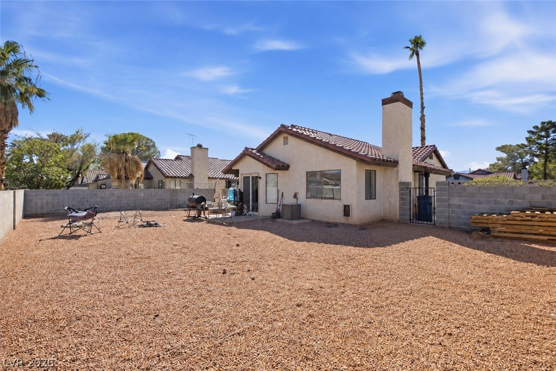 3960 Grapefruit Circle, Las Vegas, NV 89103 An enclosed desert-landscaped backyard surrounds this classic stucco residence under blue skies.