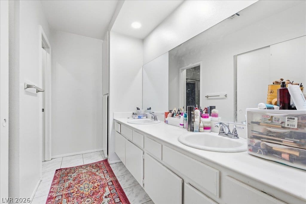 3960 Grapefruit Circle, Las Vegas, NV 89103 A large vanity, 2 sinks and a mirror complements the tile flooring in this functional bathroom.