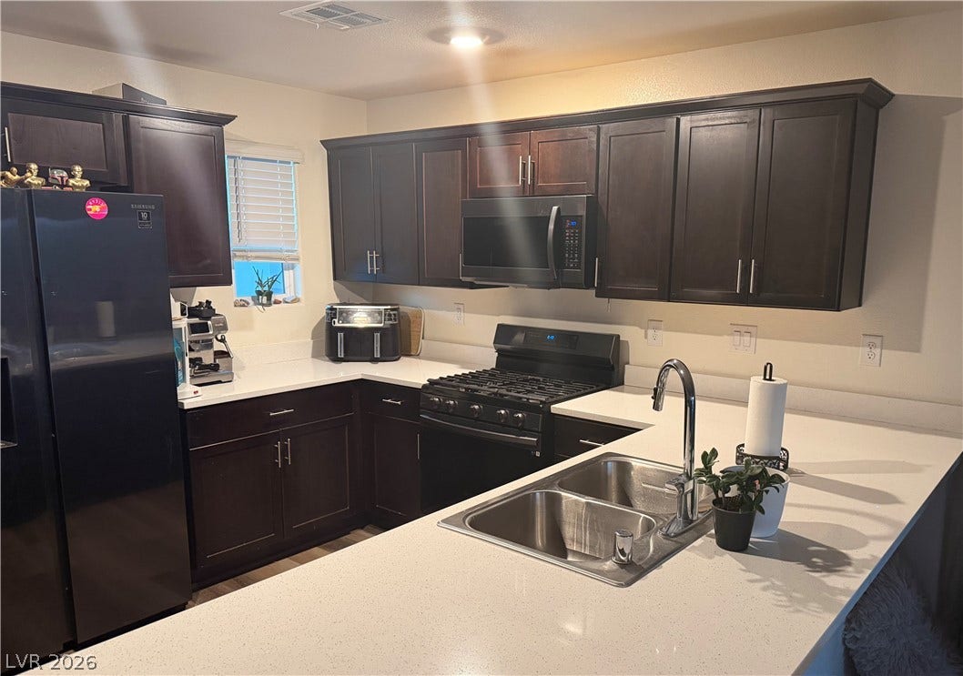 10079 Vibrant Moon Avenue, Las Vegas, NV 89129 A well-appointed kitchen showcasing rich cabinetry, sleek countertops, and modern black appliances.