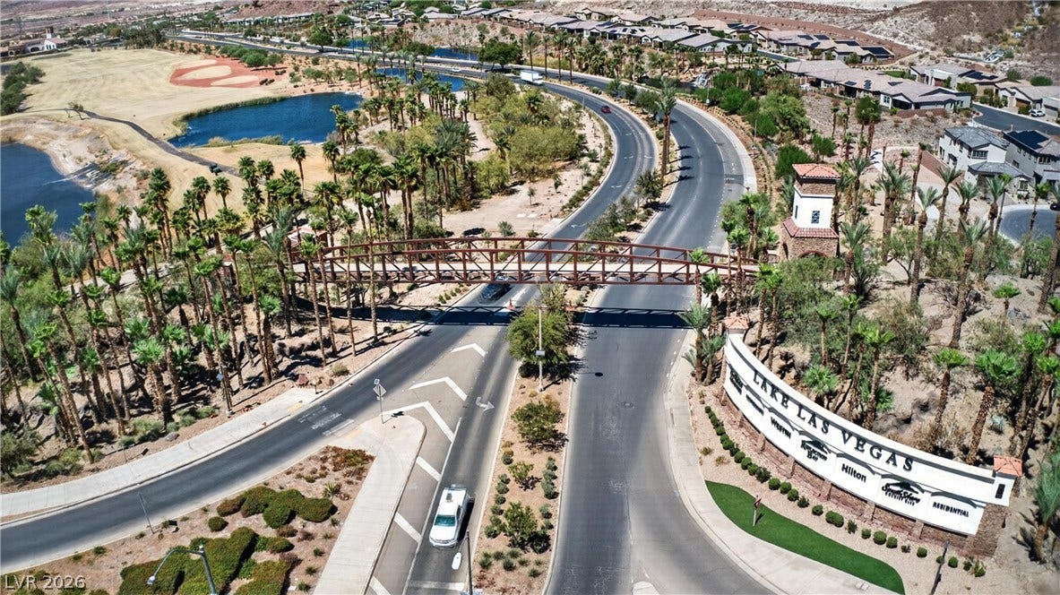 4 Bobado Lane, Henderson, NV 89011 An aerial perspective captures the entrance road, pedestrian bridge, and surrounding palm-lined parkways.