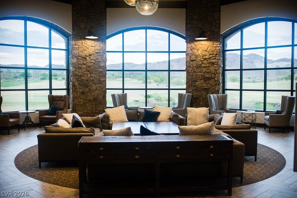 4 Bobado Lane, Henderson, NV 89011 Massive arched windows frame scenic mountain vistas alongside rustic stone-accented walls and wood-look flooring.