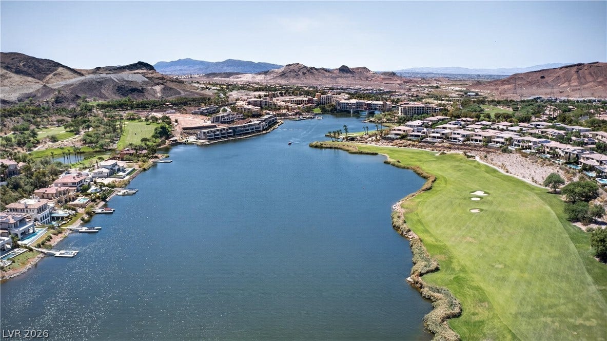 4 Bobado Lane, Henderson, NV 89011 Dramatic mountain ranges frame a sprawling blue lake bordered by a manicured golf course fairway.