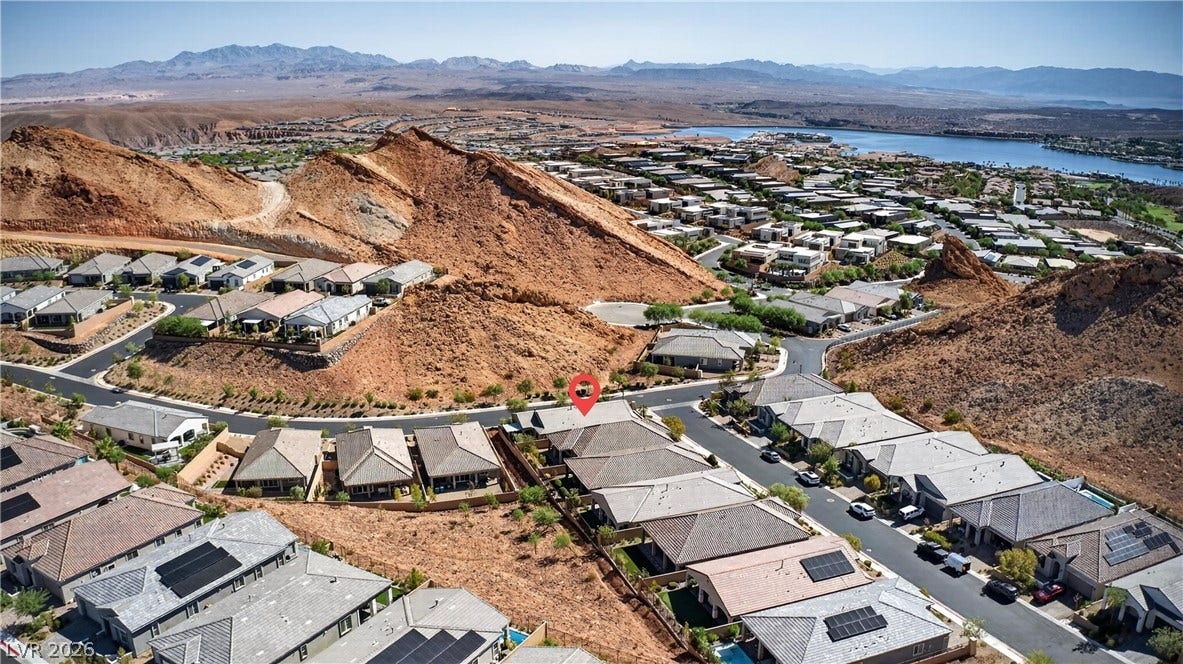 4 Bobado Lane, Henderson, NV 89011 An aerial perspective showcases a neighborhood nestled against dramatic desert hills near a distant lake.