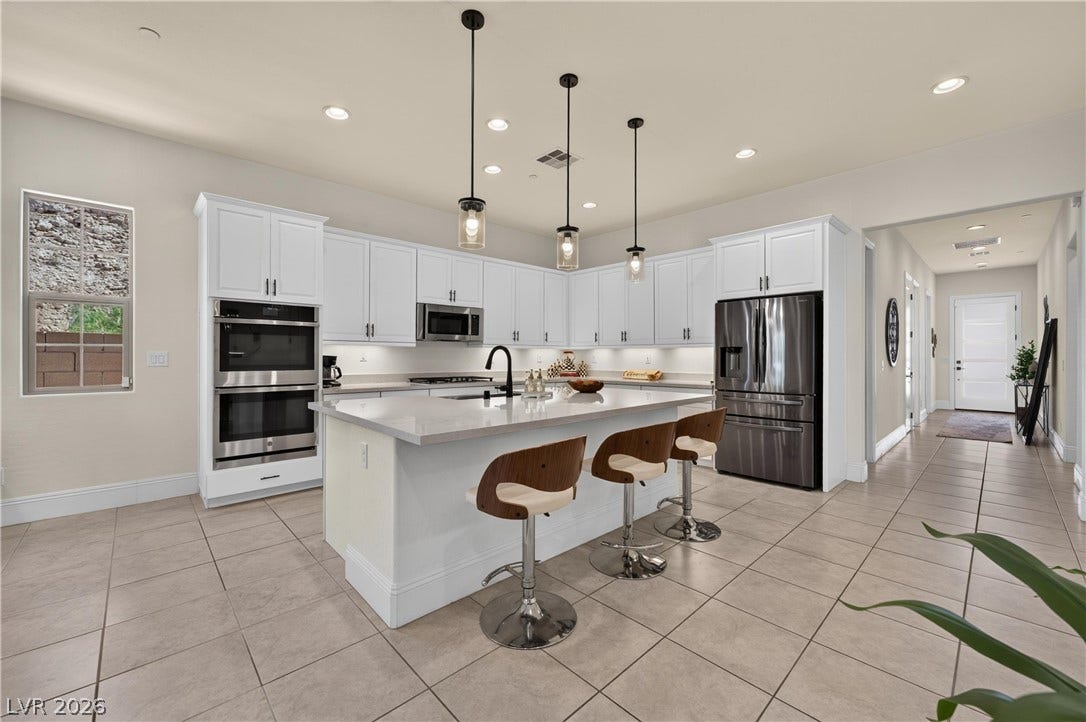 4 Bobado Lane, Henderson, NV 89011 White cabinetry and an expansive central island anchor this light-filled modern kitchen.