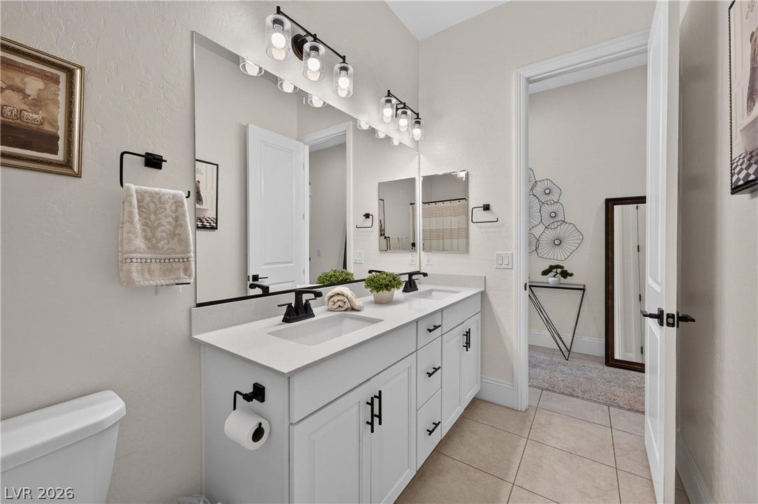 4 Bobado Lane, Henderson, NV 89011 Double vanities with stone counters and modern fixtures anchor this bright bathroom.