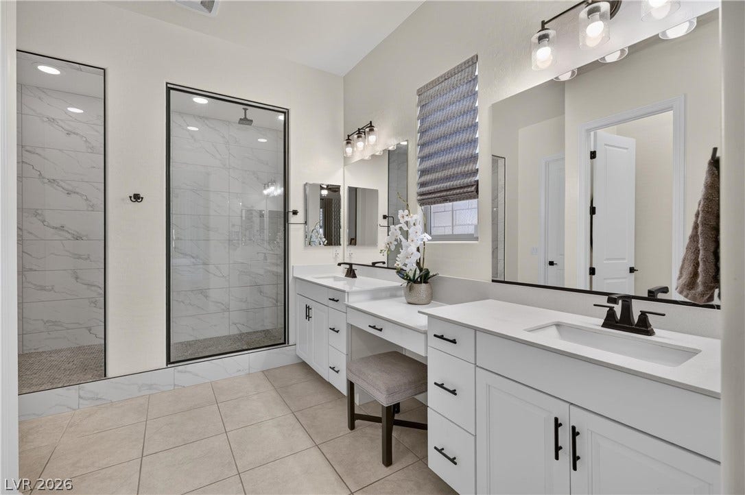 4 Bobado Lane, Henderson, NV 89011 A spacious vanity area with stone counters sits adjacent to a glass-enclosed walk-in shower.
