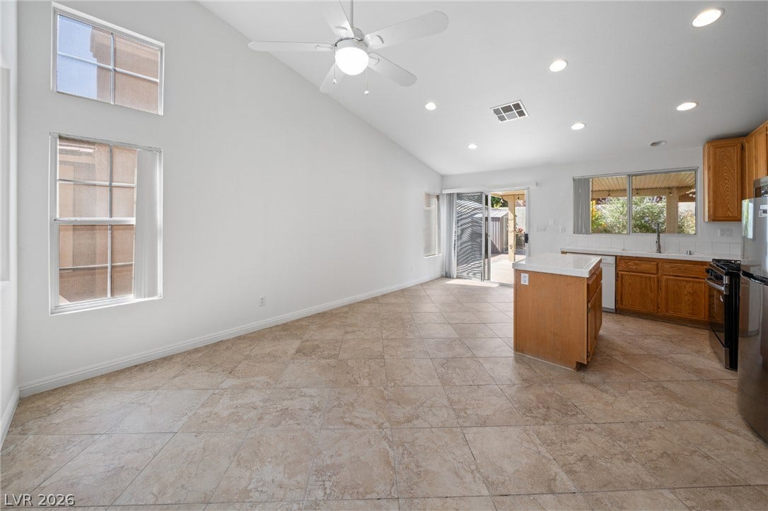 Tiled flooring flows through an open-concept living and kitchen area highlighted by vaulted ceilings.