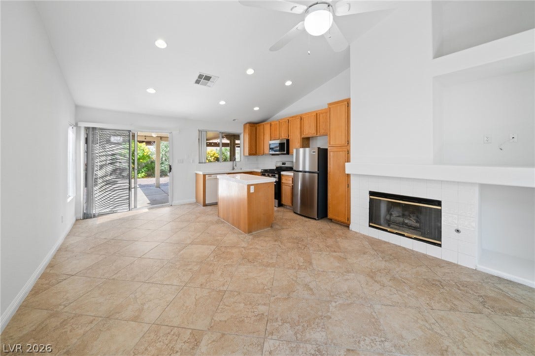 Tile flooring and a cozy fireplace anchor this open-concept kitchen and living area.
