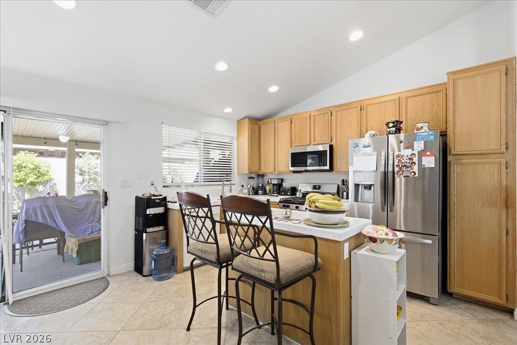 Natural wood cabinetry and recessed lighting define this functional culinary space with tile flooring.