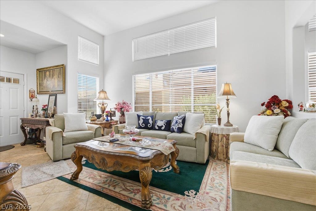 Towering ceilings and multi-tiered windows illuminate this welcoming tiled living area.