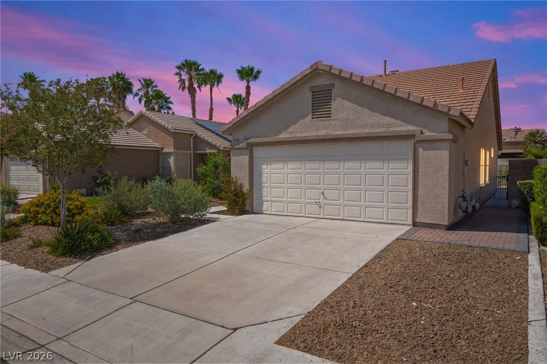 A spacious concrete driveway leads directly to a secure two-car garage under classic tiled roofing.
