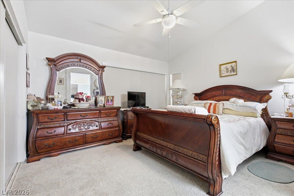 A spacious bedroom offers plush neutral carpeting and vaulted ceilings overhead.