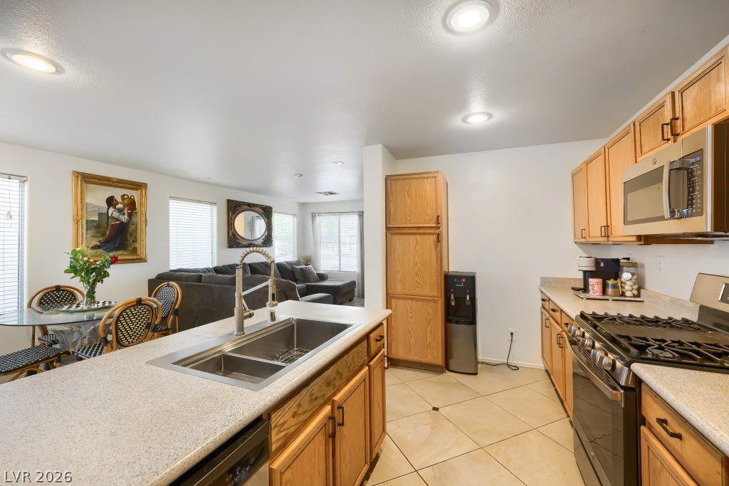 2099 Lost Maple Street, Las Vegas, NV 89115 An open-concept kitchen features warm wood cabinetry, stone countertops, and durable tile flooring.