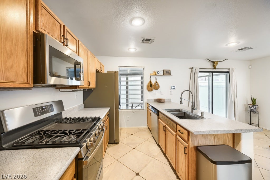2099 Lost Maple Street, Las Vegas, NV 89115 Gleaming tile floors and natural wood cabinetry anchor this functional open kitchen space.