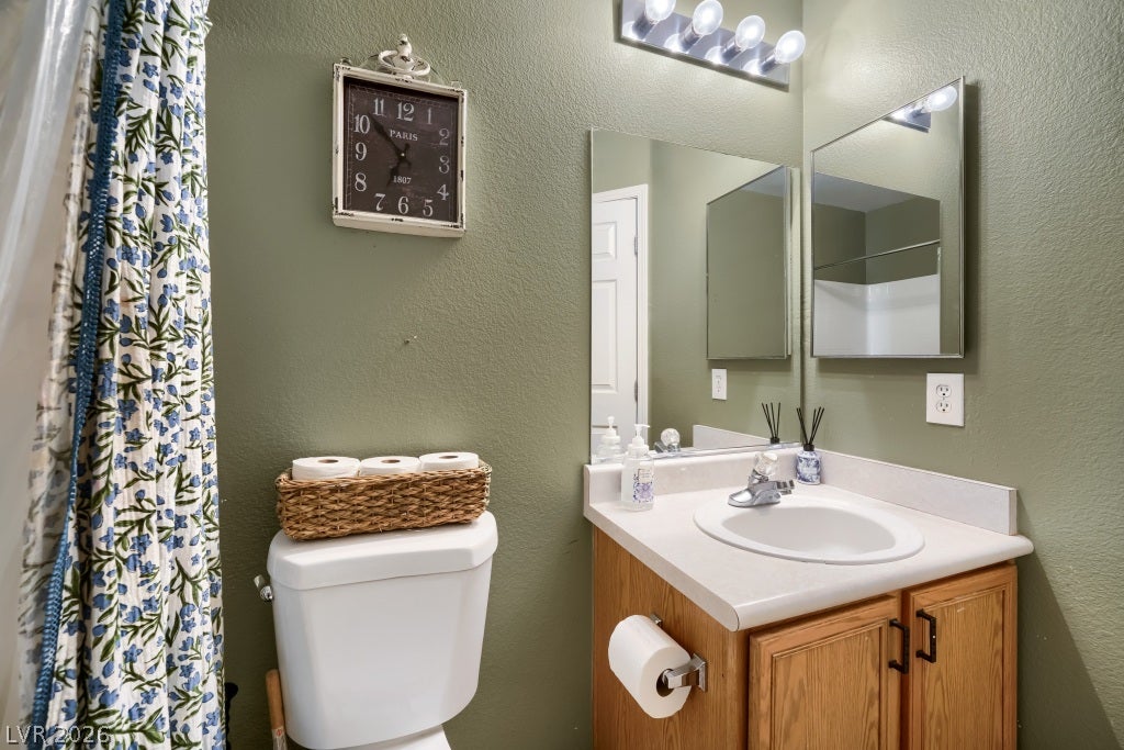 2099 Lost Maple Street, Las Vegas, NV 89115 A classic wooden vanity pairs with large mirrors in this functional bathroom space.