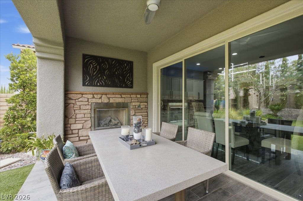 181 Elder View Drive, Las Vegas, NV 89138 An inviting outdoor living space features a stone-clad fireplace and sliding glass doors, perfect for al fresco dining.