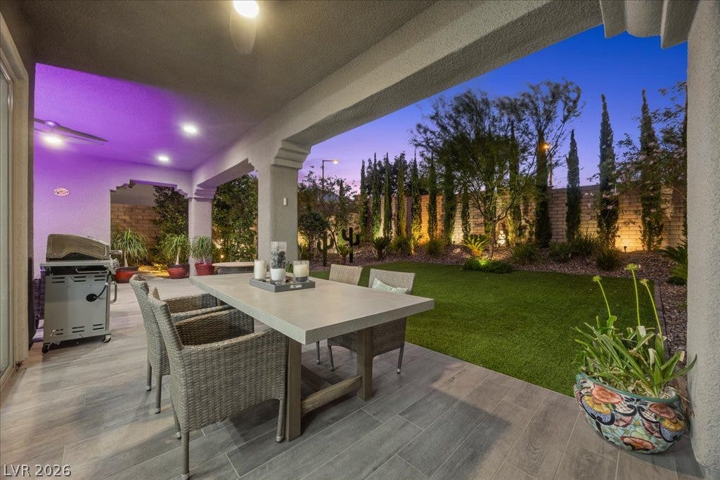 181 Elder View Drive, Las Vegas, NV 89138 A spacious covered patio overlooks a manicured green lawn framed by architectural columns and mature trees.