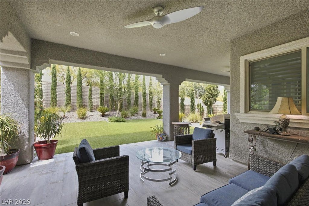 181 Elder View Drive, Las Vegas, NV 89138 An inviting covered patio features sleek tile flooring, offering a seamless transition to the vibrant, manicured lawn.