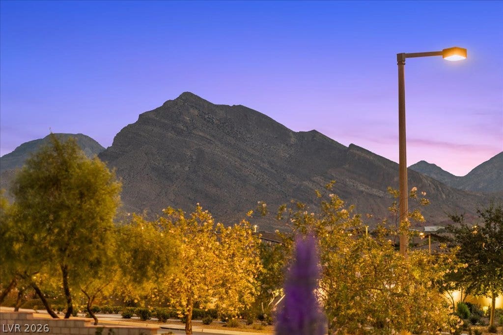 181 Elder View Drive, Las Vegas, NV 89138 Dramatic mountain vistas rise above the surrounding neighborhood trees under a twilight sky.