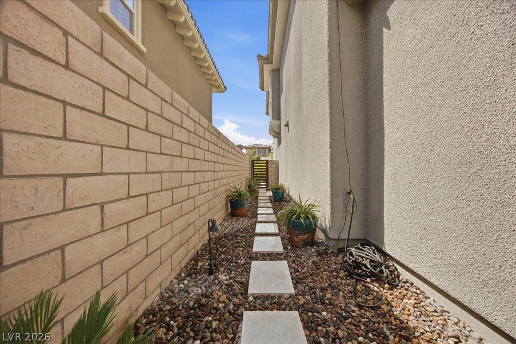 181 Elder View Drive, Las Vegas, NV 89138 A stone stepping stone path winds through gravel alongside a high block privacy wall.