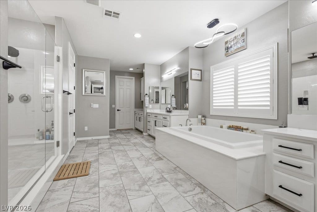 181 Elder View Drive, Las Vegas, NV 89138 A naturally illuminated bathroom showcases a spacious walk-in shower and a deep soaking tub, complemented by dual vanities.
