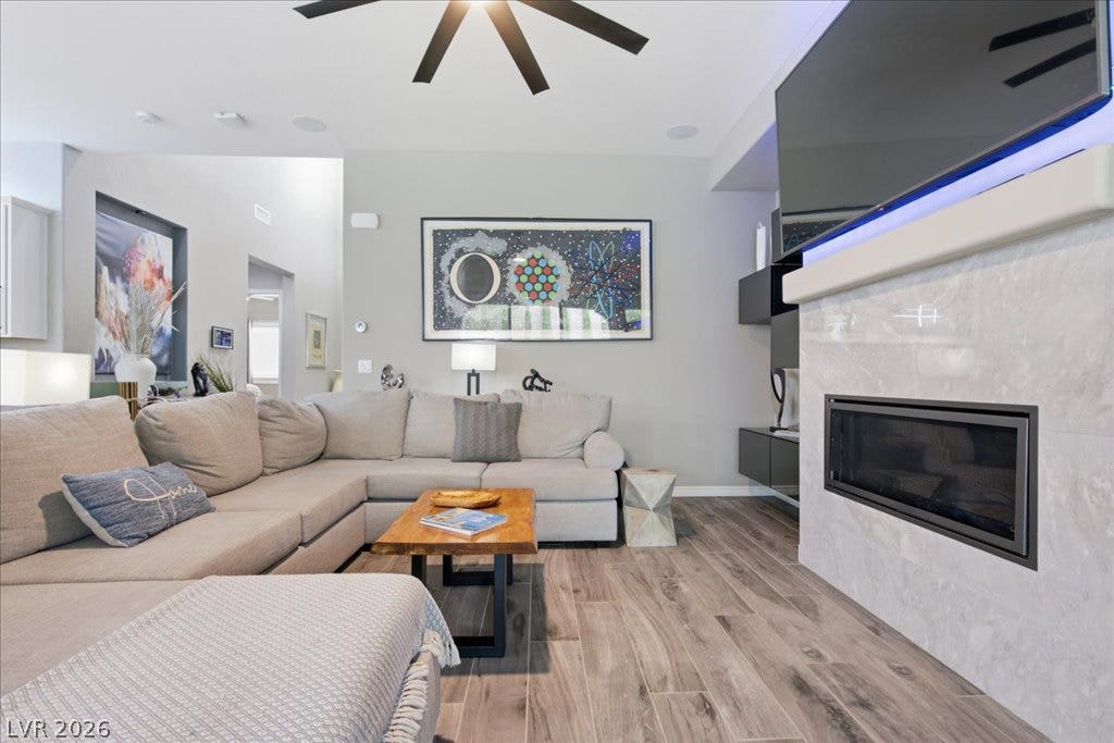181 Elder View Drive, Las Vegas, NV 89138 A contemporary living room features wood-look tile flooring and a sleek fireplace for cozy gatherings.