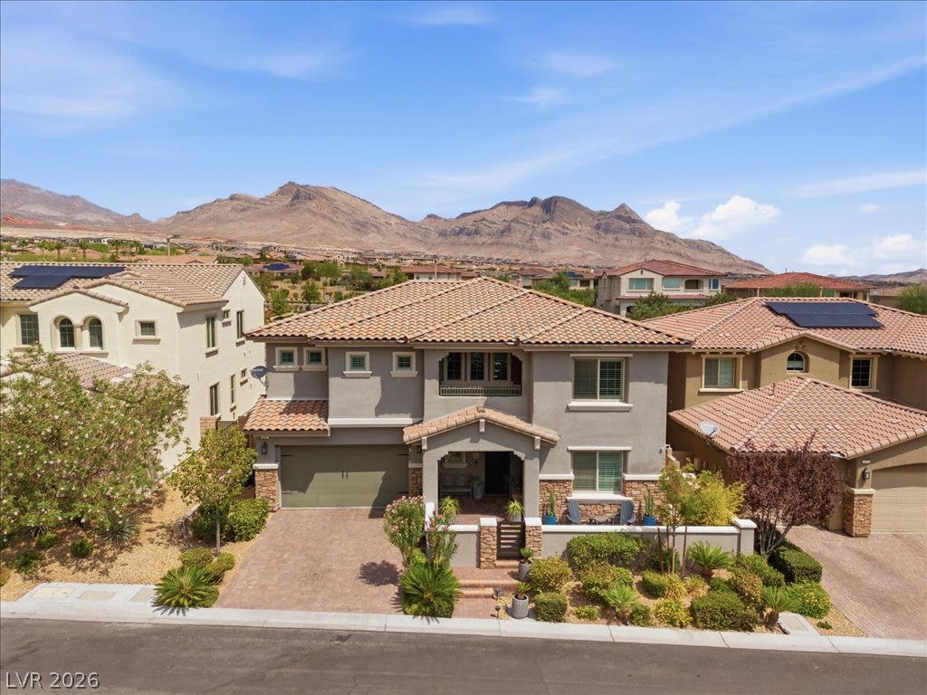181 Elder View Drive, Las Vegas, NV 89138 Dramatic mountain backdrops frame this elegant multi-level home featuring brick accents and a paved driveway.