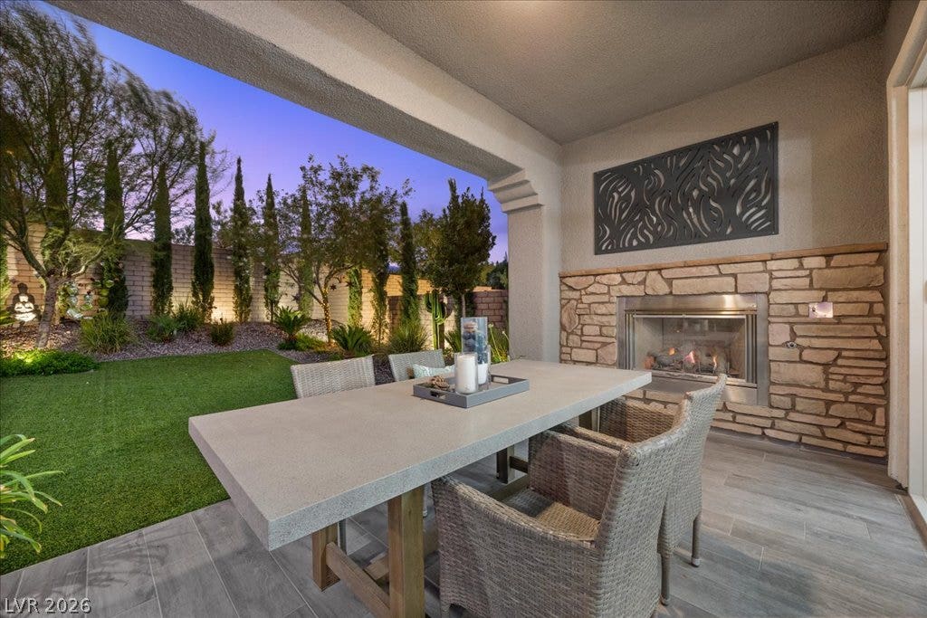 181 Elder View Drive, Las Vegas, NV 89138 An inviting covered patio offers a stone fireplace and tiled flooring overlooking the manicured yard.