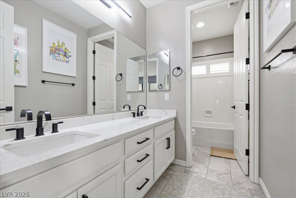 181 Elder View Drive, Las Vegas, NV 89138 Marble-look countertops and sleek black fixtures elevate this well-appointed bathroom.