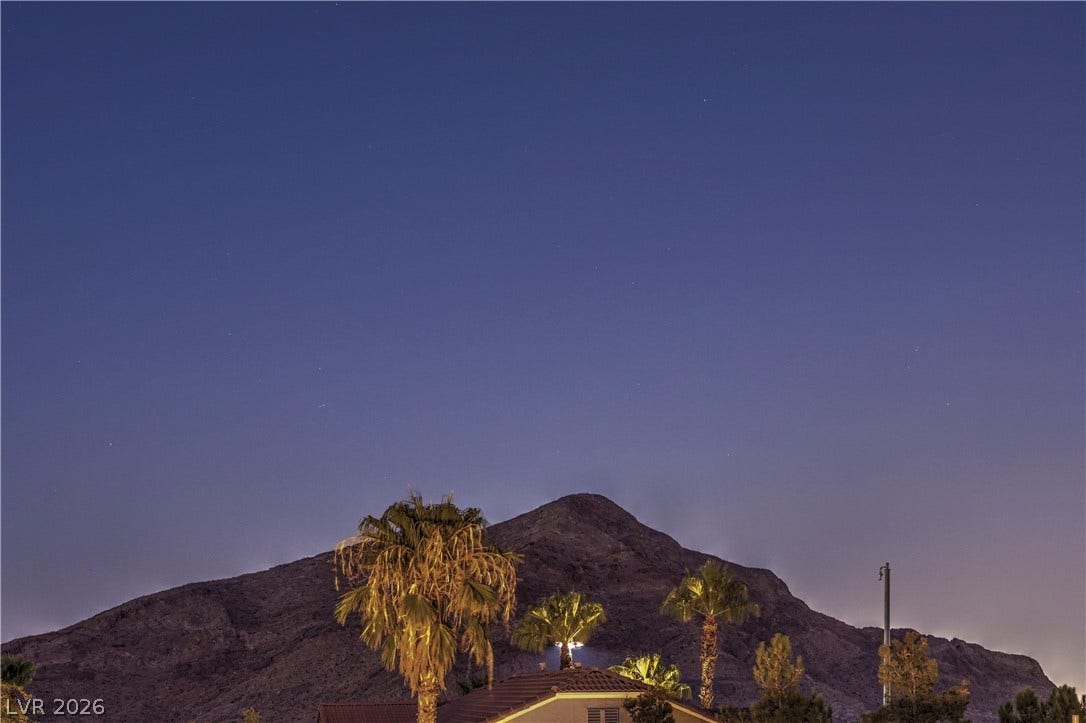10474 Rustyville Court, Las Vegas, NV 89129 A tranquil night sky stretches above mountain vistas, palms, and rooftops.