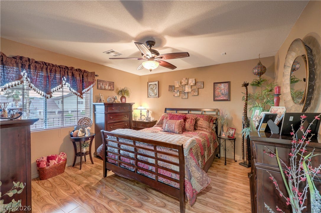 10474 Rustyville Court, Las Vegas, NV 89129 A well-lit bedroom featuring rich LVP flooring and a ceiling fan, offering a comfortable personal retreat.