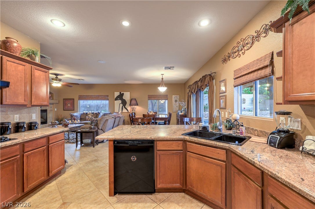 10474 Rustyville Court, Las Vegas, NV 89129 An inviting open-concept kitchen features rich wood cabinetry, granite countertops, and seamless views into the living and dining areas.