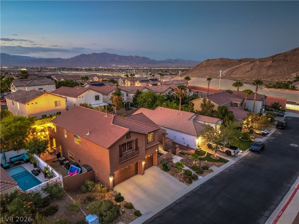 10474 Rustyville Court, Las Vegas, NV 89129 An aerial perspective reveals a vibrant neighborhood with mountain views, showcasing private pools and meticulous landscaping.