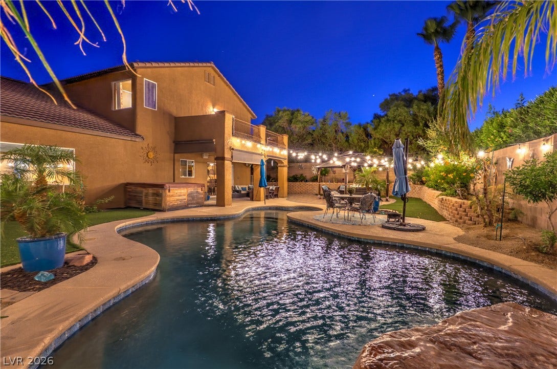 10474 Rustyville Court, Las Vegas, NV 89129 An inviting backyard oasis offers a pebbletec pool, hot tub, and festive string lighting for evening entertaining.