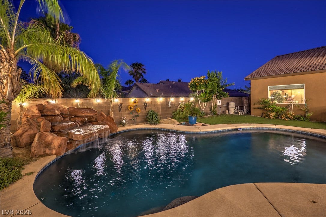 10474 Rustyville Court, Las Vegas, NV 89129 A tranquil backyard oasis features a rock waterfall spilling into a sparkling private pool.