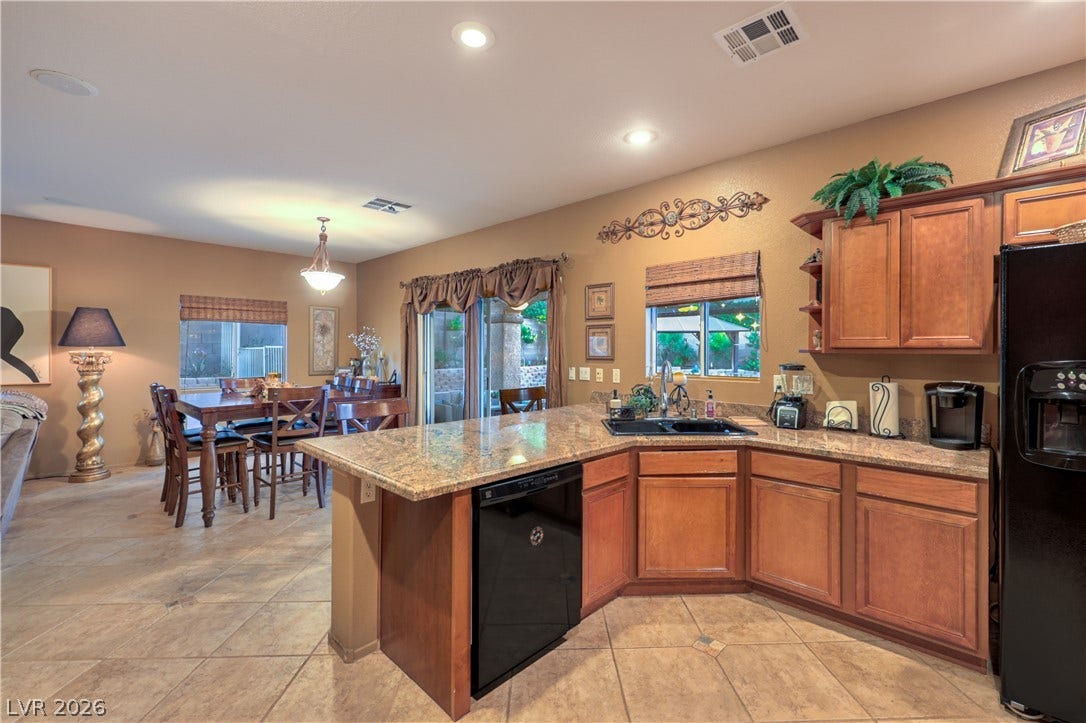 10474 Rustyville Court, Las Vegas, NV 89129 Granite counters and rich wood cabinetry define this inviting, naturally illuminated kitchen and dining area.