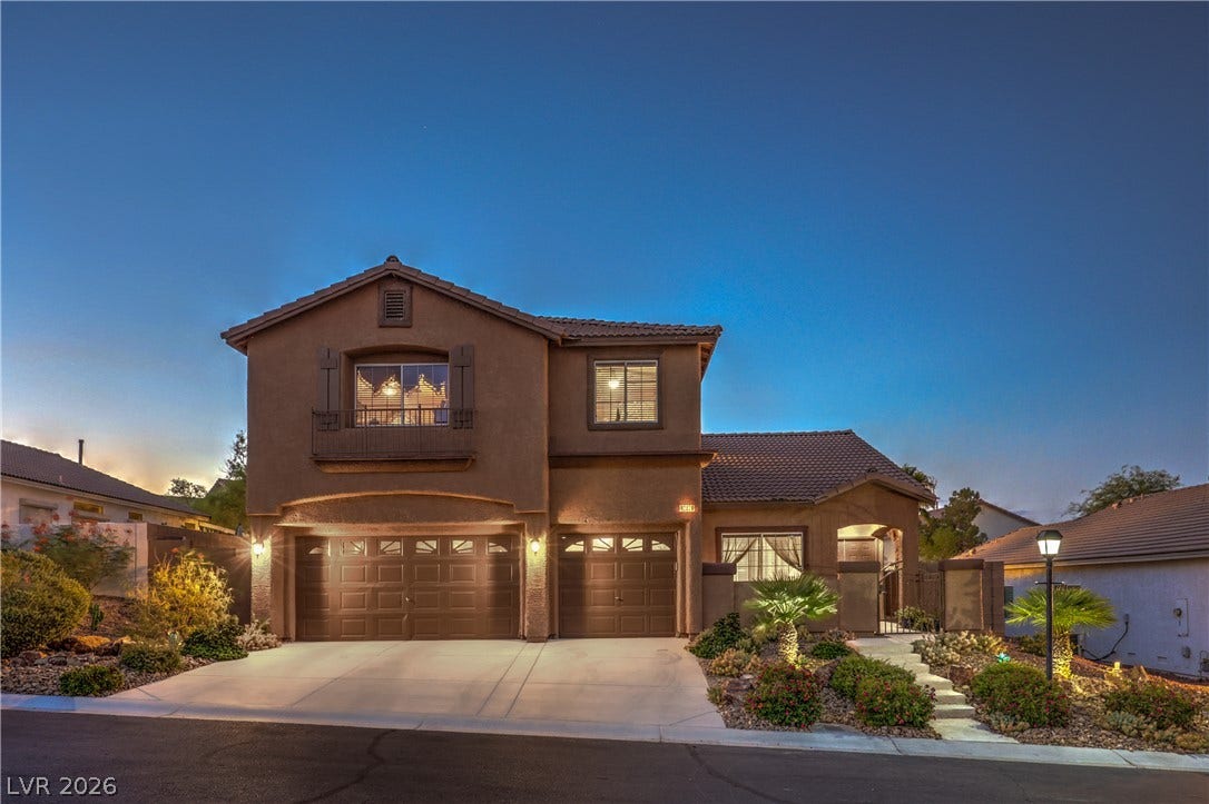 10474 Rustyville Court, Las Vegas, NV 89129 A welcoming facade showcases a large driveway, dual garage doors, and well-maintained desert landscaping leading to the entrance.