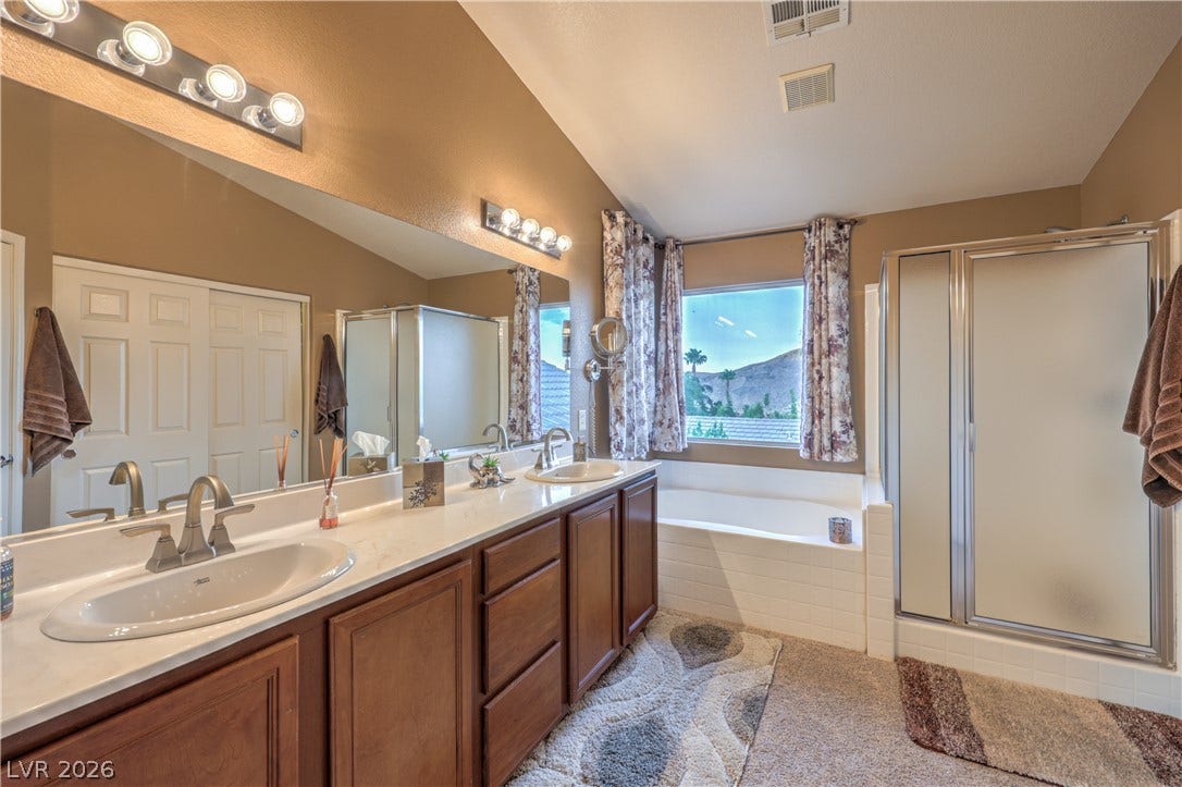 10474 Rustyville Court, Las Vegas, NV 89129 Dual vanities and a deep soaking tub create a luxurious primary bathroom retreat.