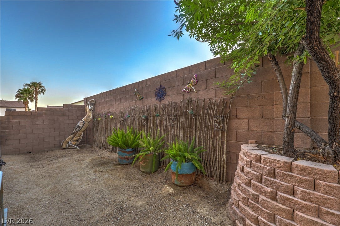 10474 Rustyville Court, Las Vegas, NV 89129 An enclosed yard with decorative block walls and a tree planted in a stone retaining wall. The is a great space for extra storage or the dog run.