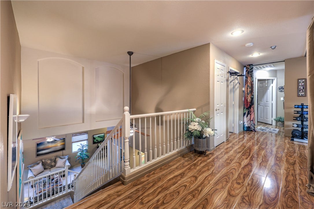 10474 Rustyville Court, Las Vegas, NV 89129 Rich wood-look flooring guides through this spacious upper-level hallway, overlooking a welcoming living area below.