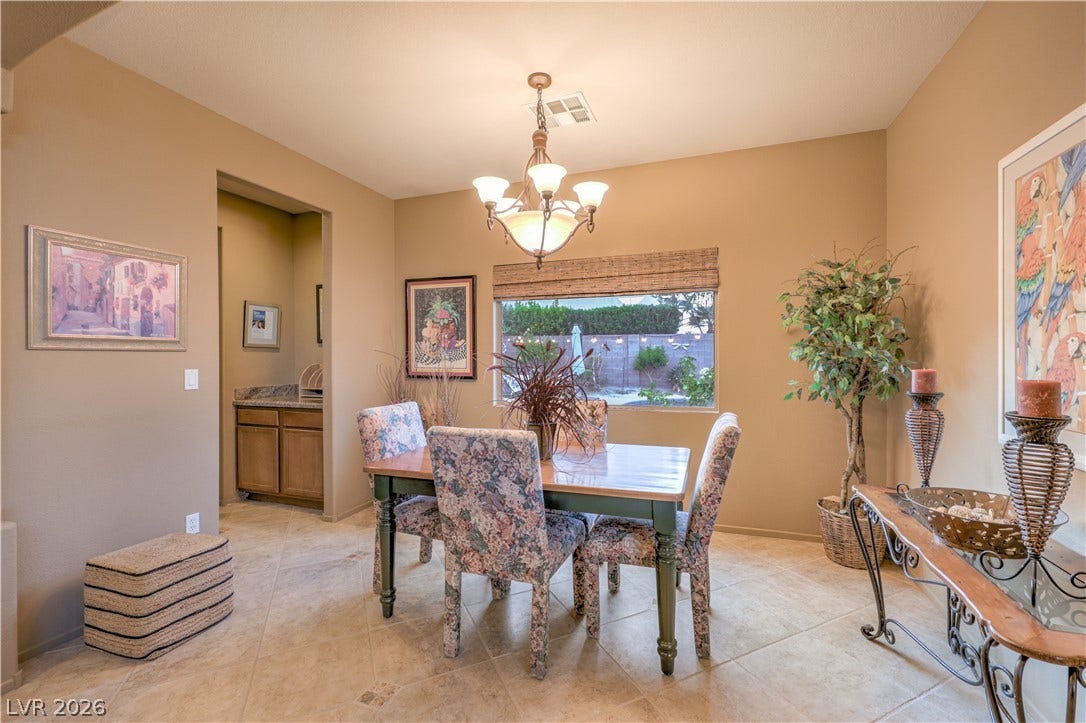 10474 Rustyville Court, Las Vegas, NV 89129 Illuminated by a contemporary chandelier, this dining area features tiled flooring and a view of the private yard.