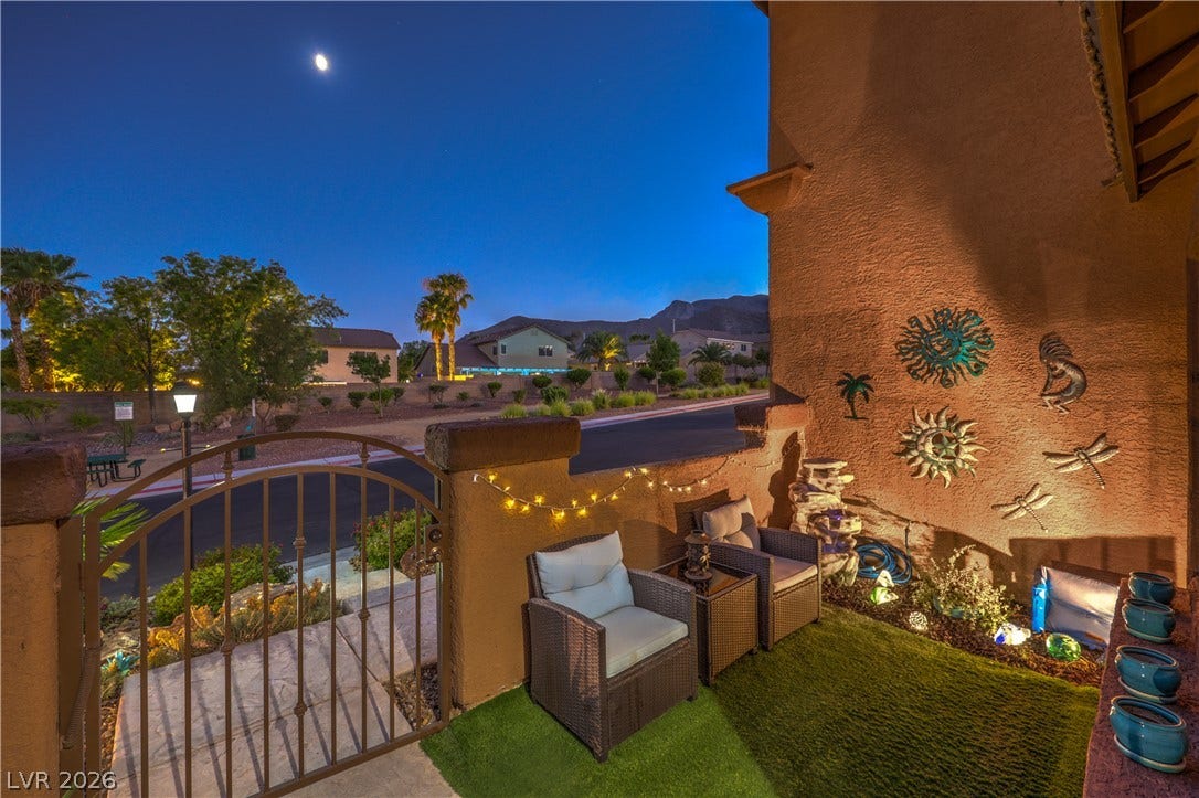 10474 Rustyville Court, Las Vegas, NV 89129 An inviting courtyard oasis under a crescent moon, featuring decorative wall art and comfortable seating.