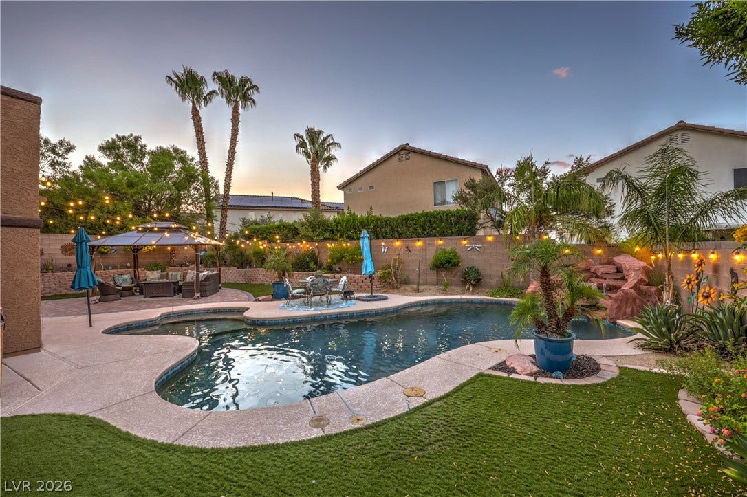 10474 Rustyville Court, Las Vegas, NV 89129 Lush landscaping surrounds a sparkling pool and cascading waterfall, creating a private outdoor oasis perfect for entertaining.