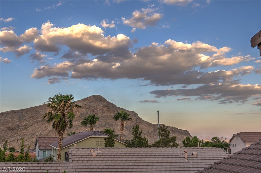 10474 Rustyville Court, Las Vegas, NV 89129 Distant mountain vistas and palm trees frame this residence, showcasing serene desert landscape views.